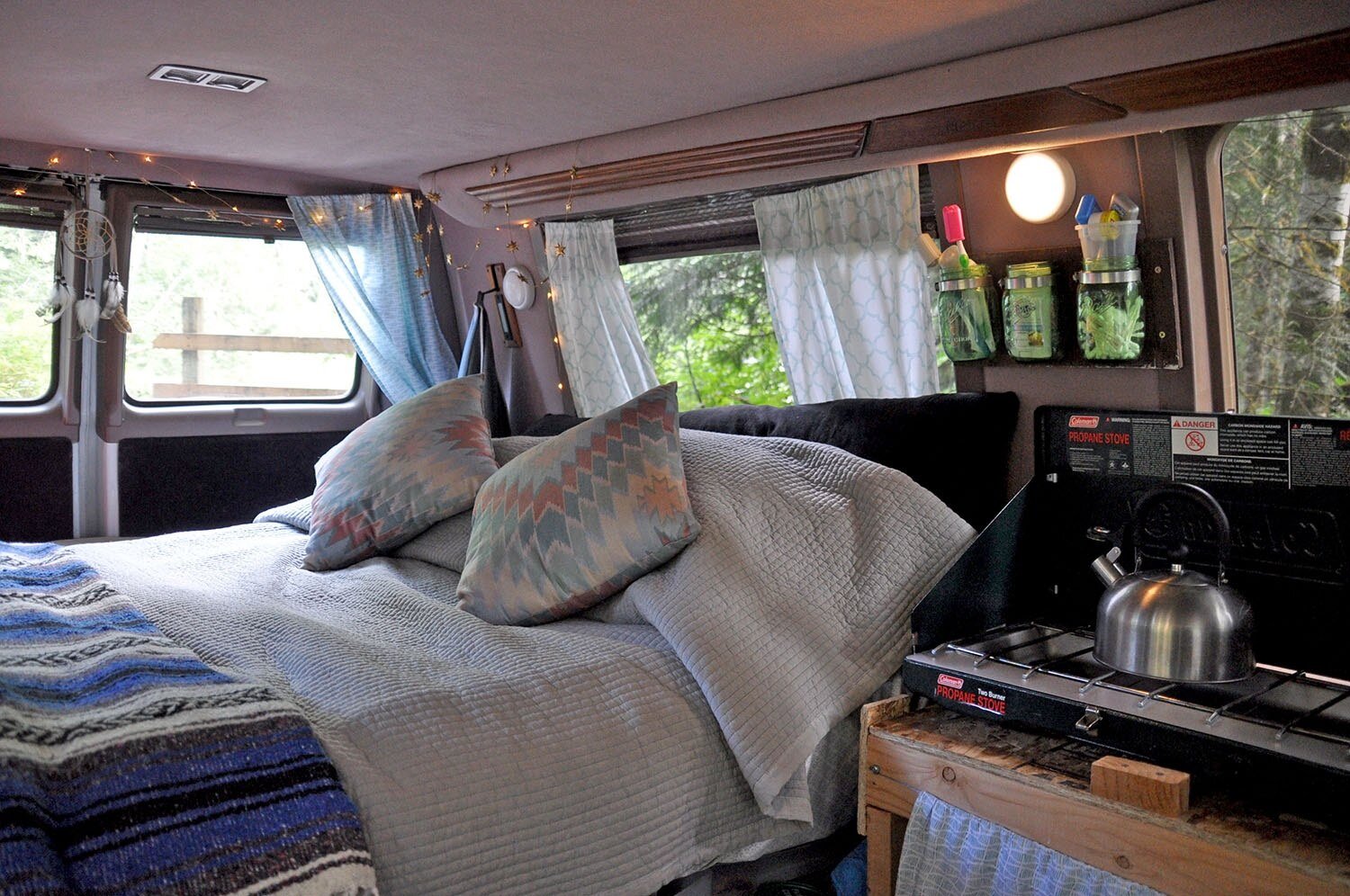 This was our first campervan bed, and we used a regular (spring) mattress that a friend was getting rid of, which barely fit inside our van. We used sheets and blankets we already had, and found pillows at a thrift store. It was a very inexpensive way to make a DIY campervan bed!
